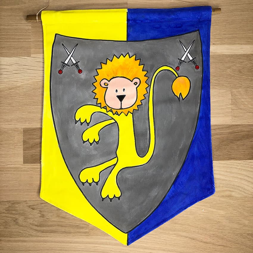 Exemple d'un blason lion peint en jaune bleu et gris près à suspendre du kit Blason imaginé par Anne Da Cunha-guillegautl pour la marque An'imato