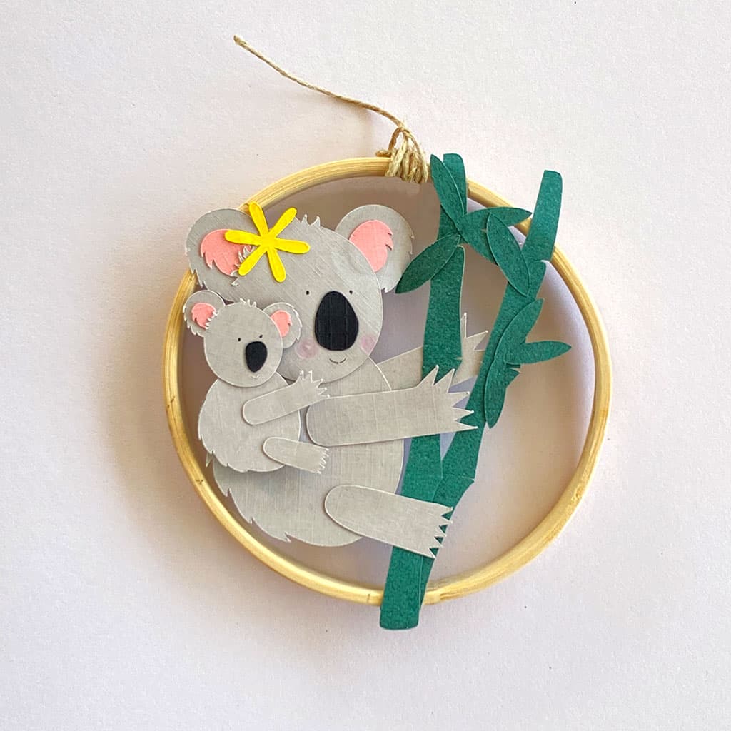Cercle décoratif avec un koala et son bébé en papiers découpés du kit imaginé Anne Da Cunha-Guillegault en exclusivité pour la marque An'imato papercut