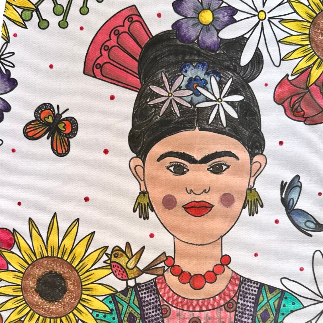Version sac à dos colorié aux feutres textiles du kit à coudre tote-bag en tissu à personnaliser peinture et broderie pour ados et adultes - motifs frida Kahlo entourée de fleur et couronne de fleurs et texte La vie est belle - Motifs imaginés par Anne Da Cunha-Guillegault en exclusivité pour la marque An'imato